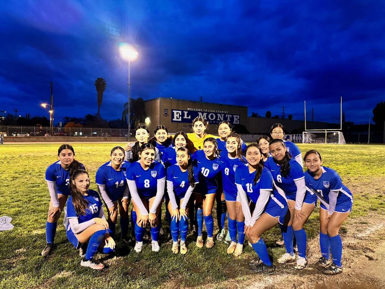 The El Monte High School girls soccer team on the field at dusk.